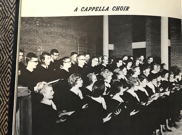 A choir singing at the front of a church, wearing robes. Picture is a photograph from a year book; text above the photos says "A Capella Choir"